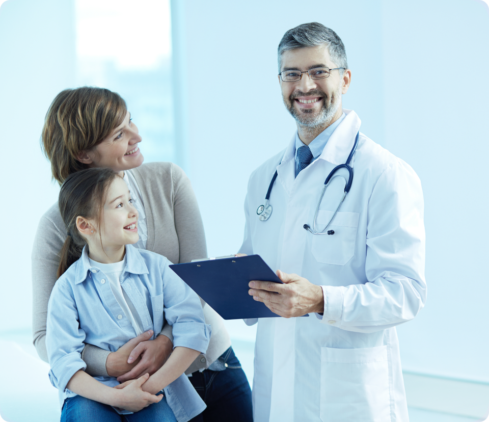 Doutor sorrindo perto da mãe e filha num consultório